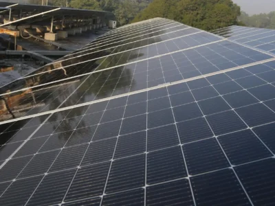 Großflächige Photovoltaikanlage mit modernen Solarmodulen auf einem Dach, umgeben von Bäumen – Beispiel für nachhaltige Energiegewinnung in Deutschland.