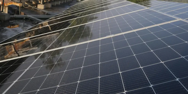 Großflächige Photovoltaikanlage mit modernen Solarmodulen auf einem Dach, umgeben von Bäumen – Beispiel für nachhaltige Energiegewinnung in Deutschland.