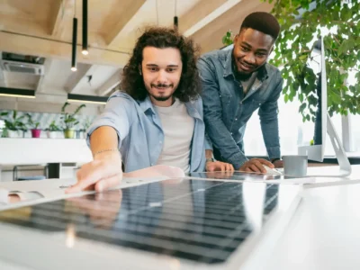 Zwei Männer betrachten ein Solarpanel, das auf dem Tisch vor ihnen liegt. Sie diskutieren über Möglichkeiten der Überschusseinspeisung.